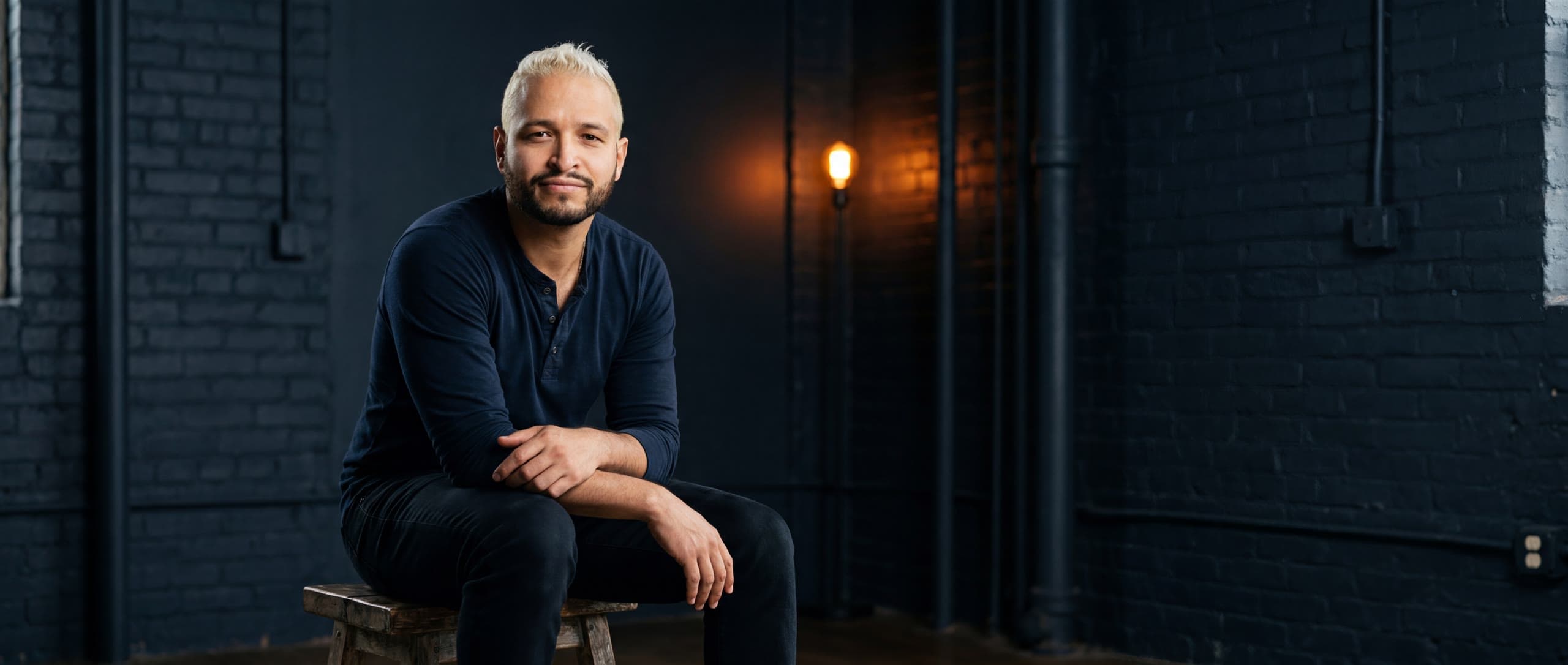 Jay seated in a moody studio, looking into the camera
